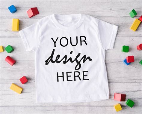 Download Kids White t-shirt mockup with unicorn toy on a wooden background.